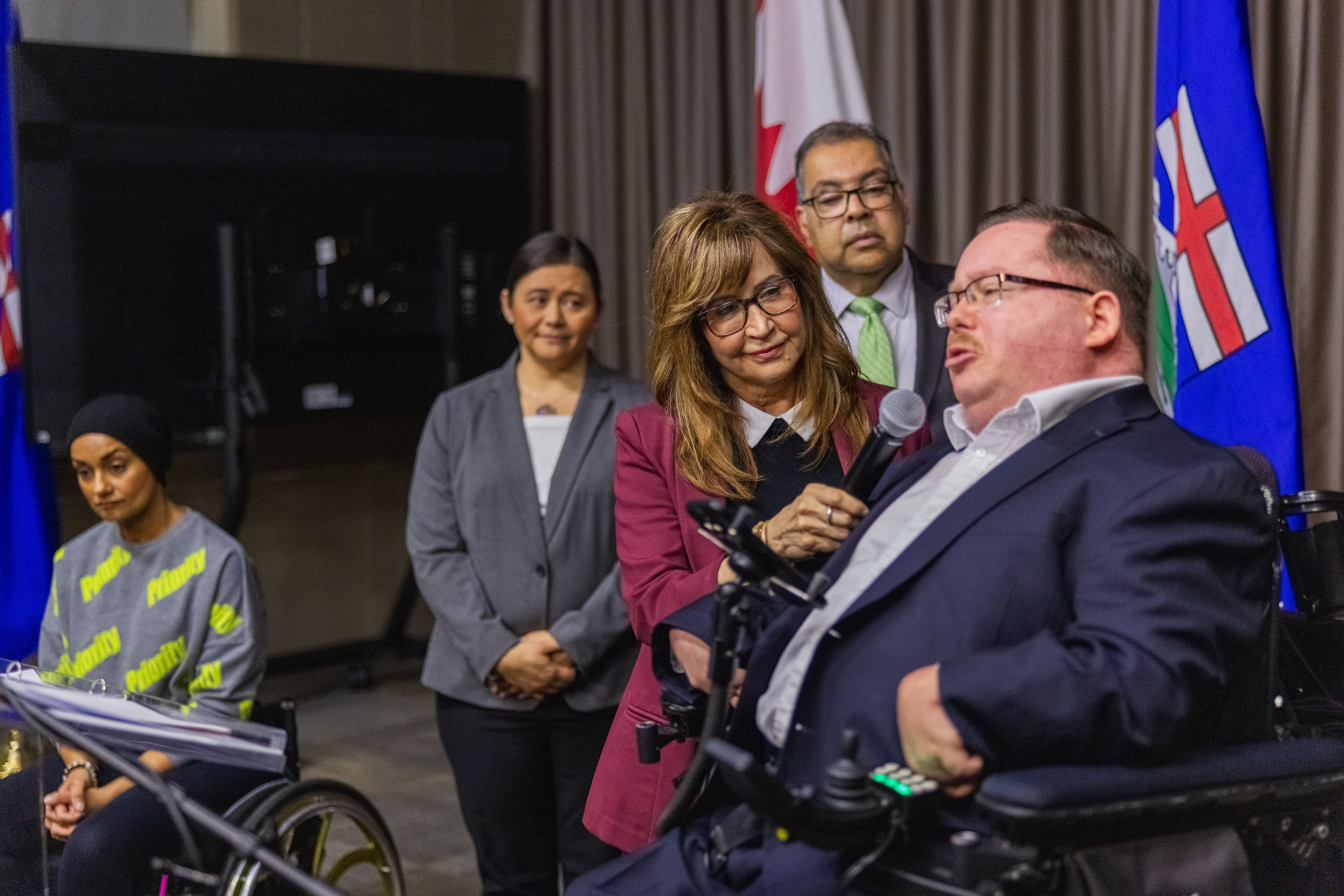 MLAs Marie Renaud and Naheed Nenshi stand at a press conference with Advocate Zachary Weeks to discuss Bill 206.