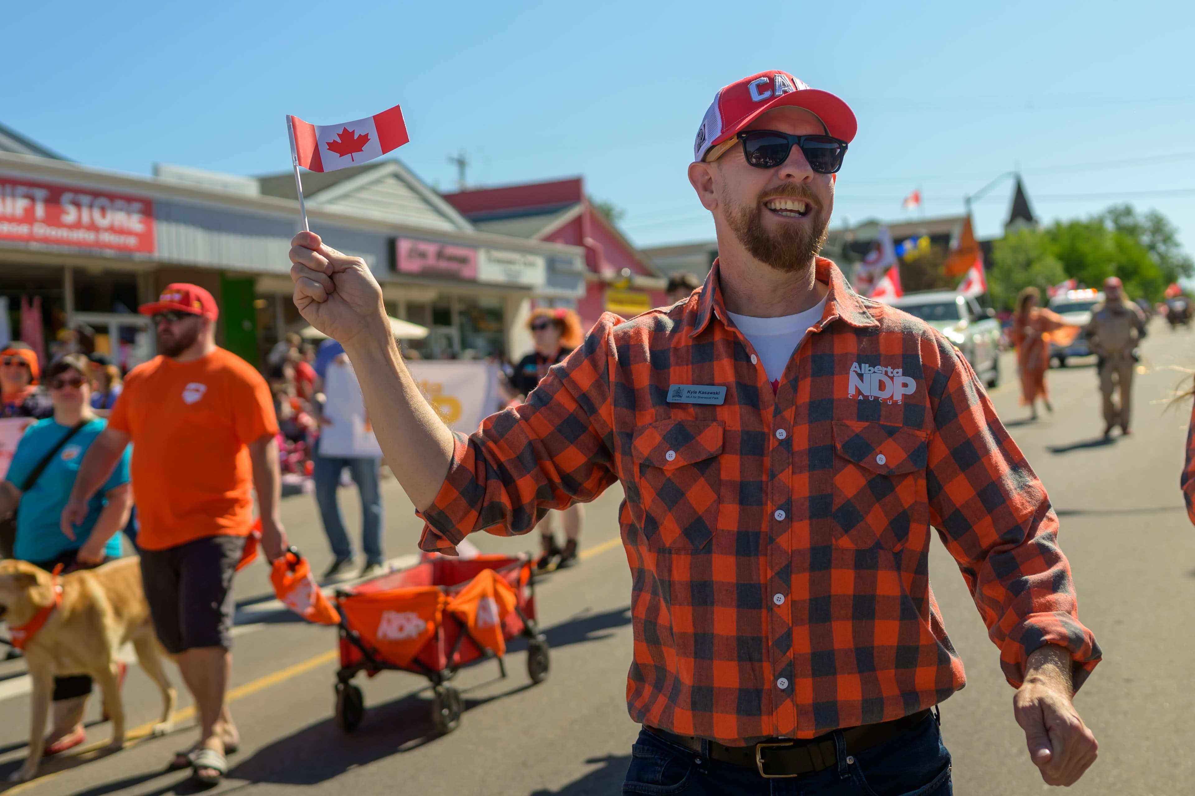 Kyle Kasawski is walking in a parade holding a Canadian flag.