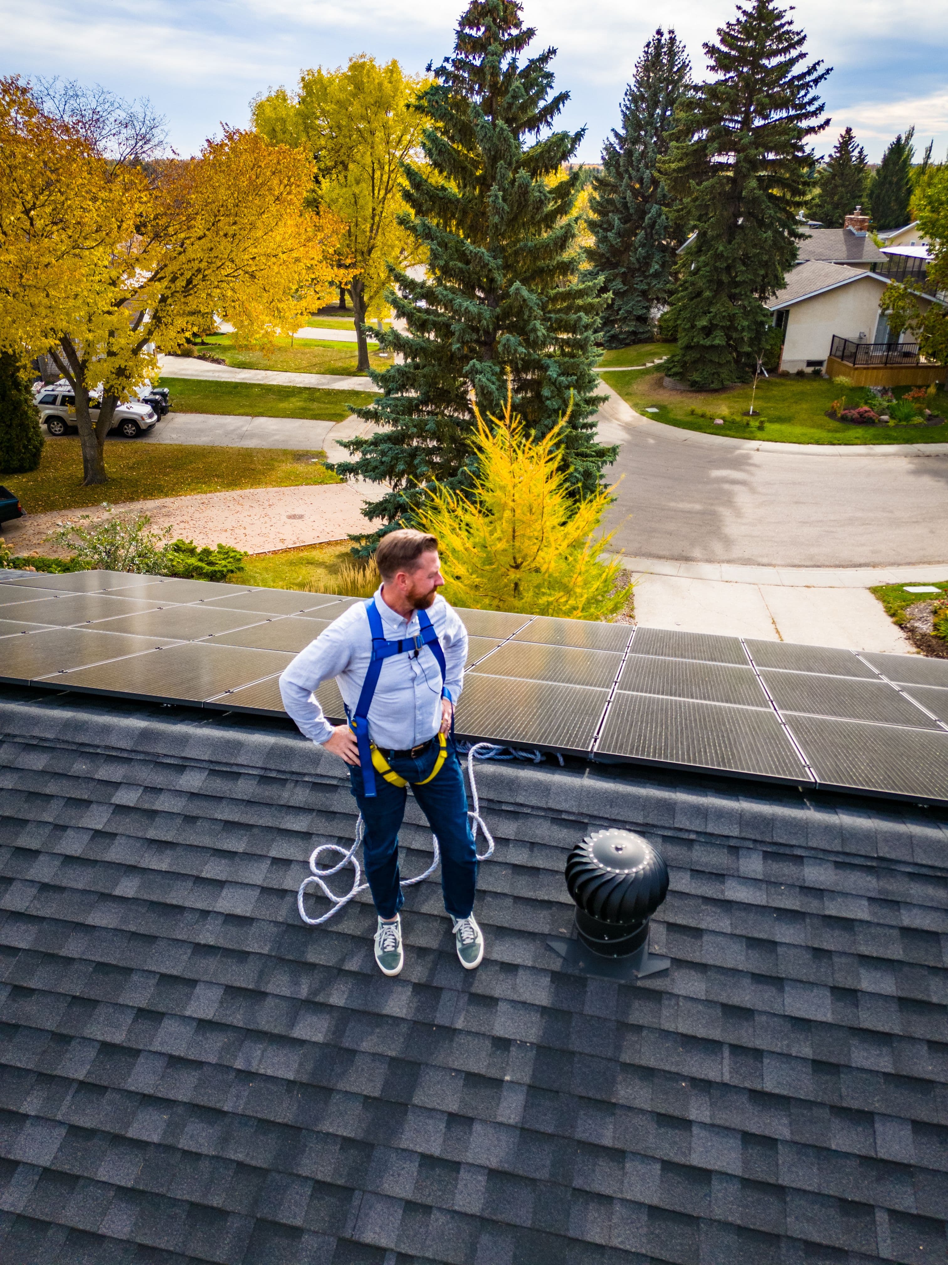 MLA Kyle Kasawski stands on a roof beside solar panels.